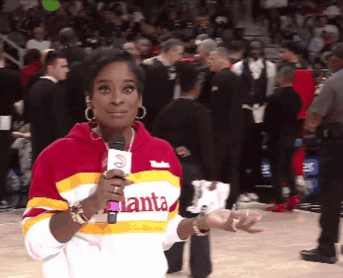 a woman wearing an atlanta sweatshirt holds a microphone in front of a crowd