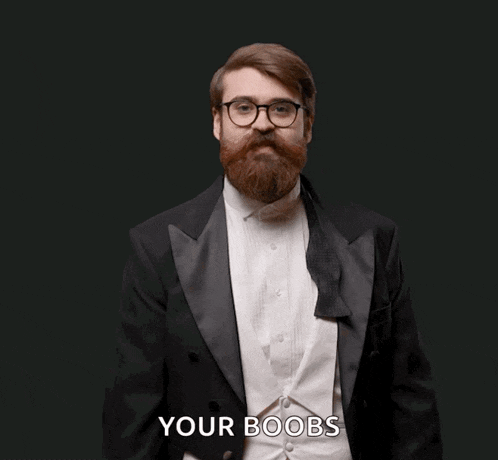 a man in a tuxedo is holding a pink wand and says your boobs