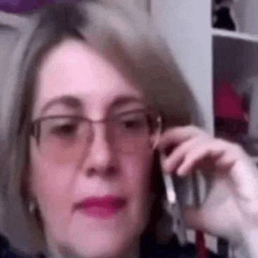 a woman is talking on a cell phone while wearing glasses .