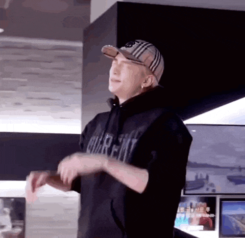 a man wearing a baseball cap and a black hoodie is dancing in a room .