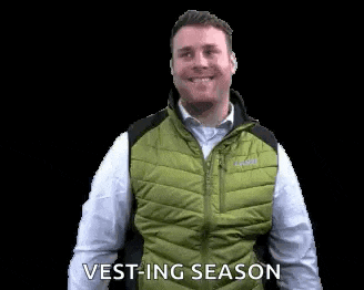 a man wearing a green vest and a white shirt is smiling and saying vest-ing season .