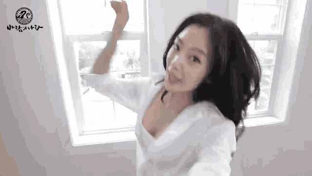 a woman in a white shirt is standing in front of a window and dancing .