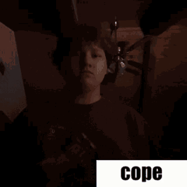 a man is standing in a dark room with the word cope below him