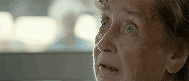 a close up of an elderly woman 's face with blue eyes