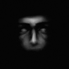 a black and white photo of a person 's face in the dark with glowing eyes .