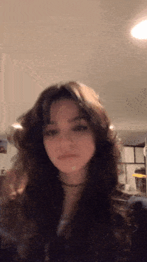 a girl with long dark hair is standing in a room .