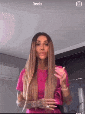 a woman in a pink shirt is holding a pink object in her hands .