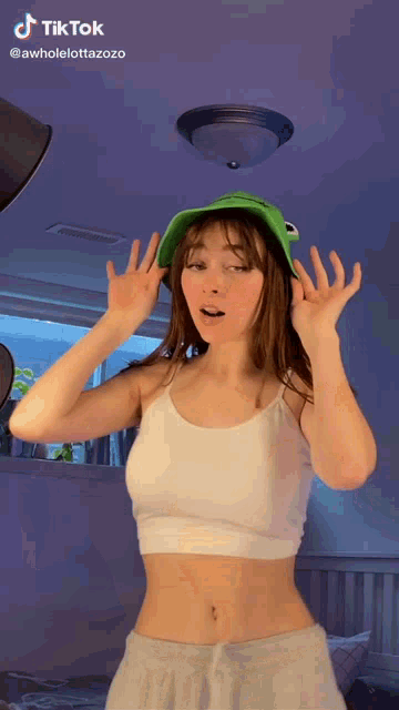 a woman wearing a frog hat and a crop top is dancing .