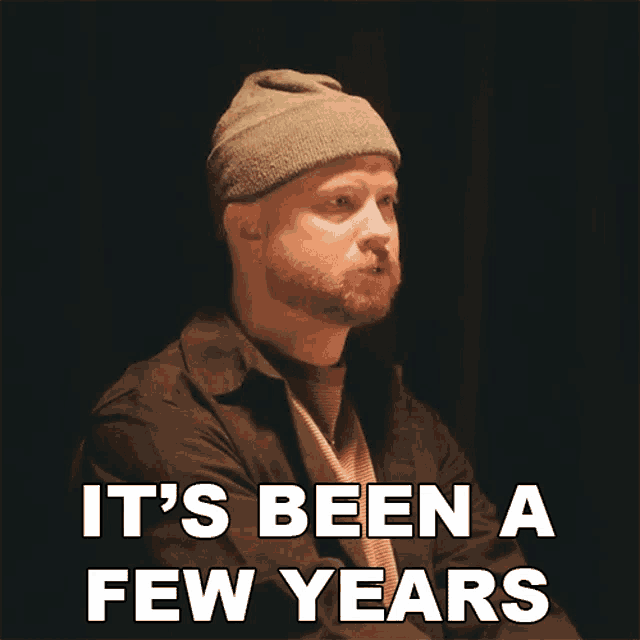 a man with a beard wearing a beanie says " it 's been a few years "