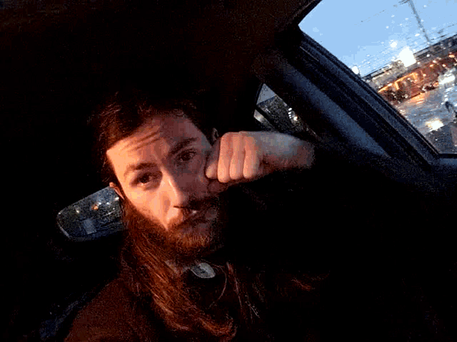 a man with a beard is sitting in a car