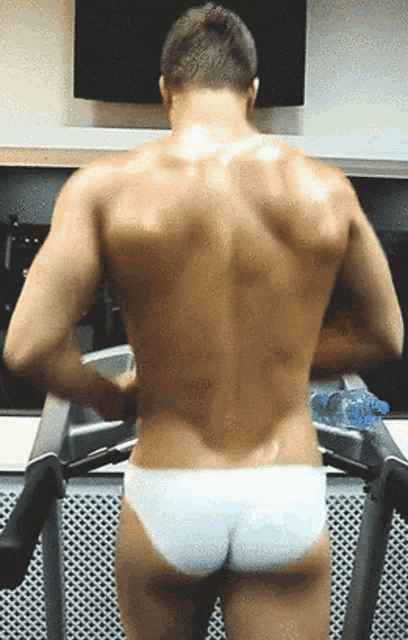 a shirtless man is standing on a treadmill