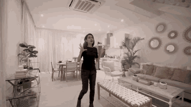 a woman is standing in a living room with a couch and a table