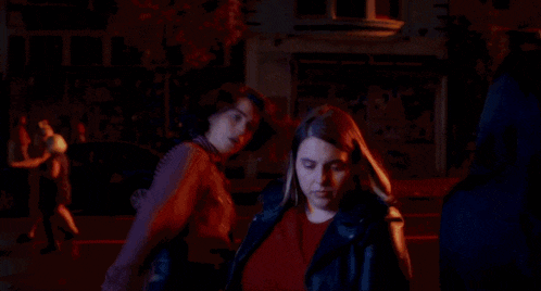 a group of women are standing in a dark room holding hands .
