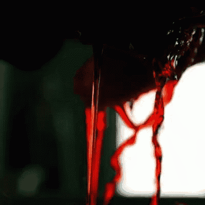 a close up of a bottle of red liquid pouring into a glass