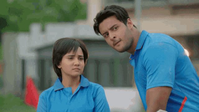 a man in a blue shirt stands next to a woman