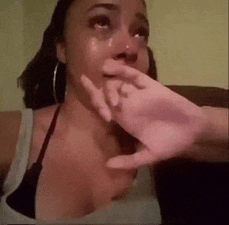 a woman is crying and covering her face with her hand while sitting on a couch .