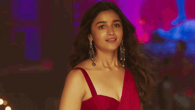a woman wearing a red dress and earrings smiles at the camera