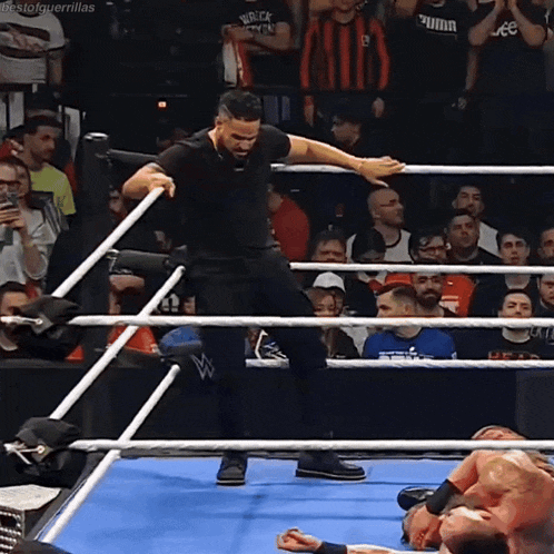 a man is standing in a wrestling ring with a crowd watching