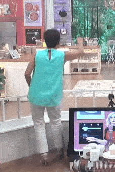 a woman in a blue top is dancing in front of a tv