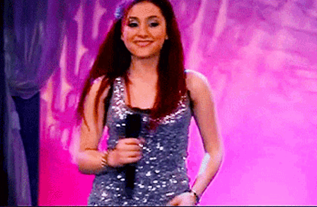 a woman in a sequined top is holding a microphone and smiling