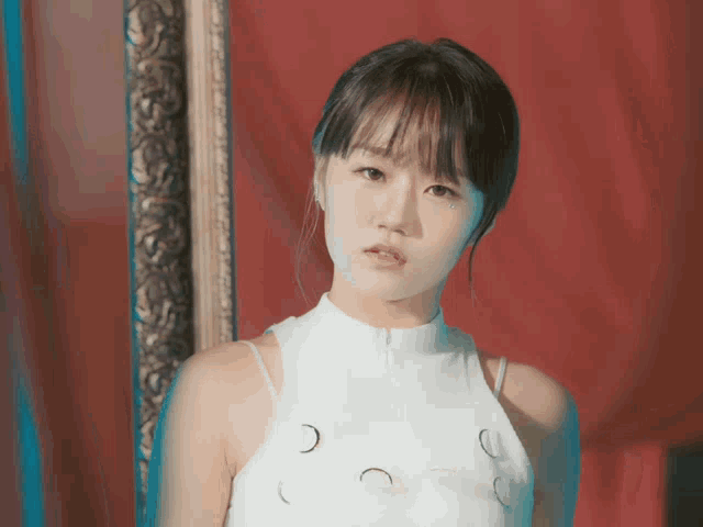 a woman in a white top stands in front of a picture frame