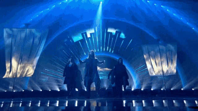 a group of people are standing on a stage in front of a blue background
