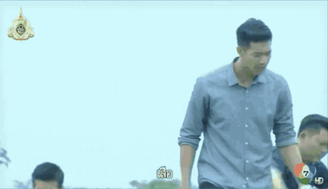 a man is laying in the grass while another man walks behind him .