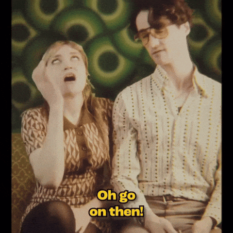 a man and a woman are sitting on a couch with the words oh go on then