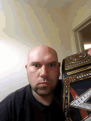 a bald man holds a world heavyweight wrestling belt