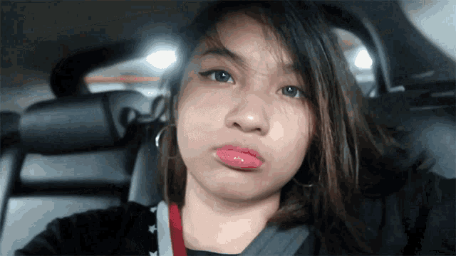 a woman sitting in the back seat of a car making a silly face