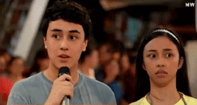 a man is speaking into a microphone while a woman looks on ..