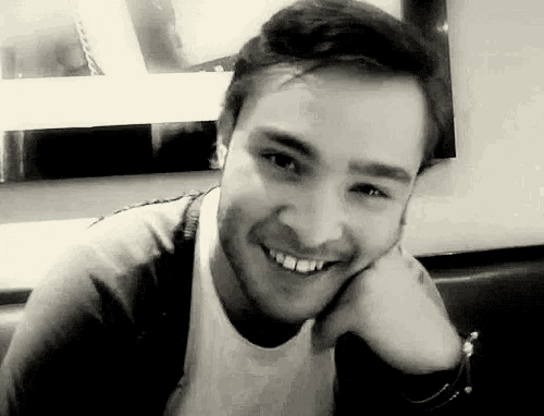 a man is smiling in a black and white photo while sitting at a table .
