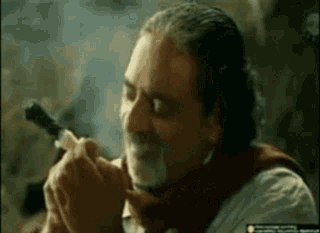 a man with a beard is smoking a cigarette while wearing a scarf .