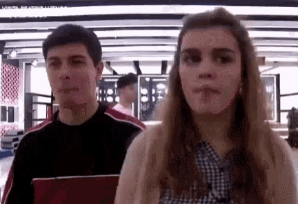 a man and a woman are standing next to each other in a room and looking at the camera .