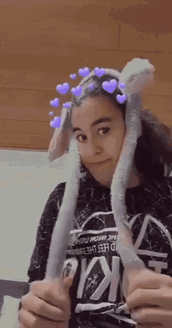 a girl wearing a bunny ear hat with hearts on it .