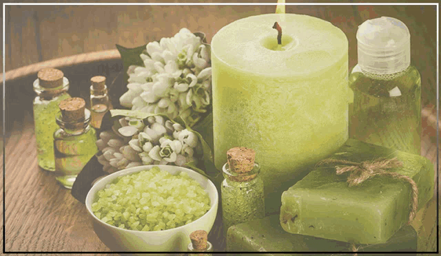 a green candle is surrounded by green soap and bottles