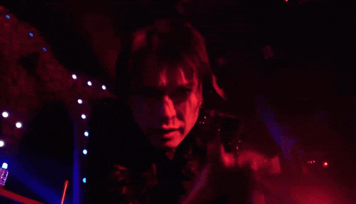 a person is standing in a dark room with red and blue lights