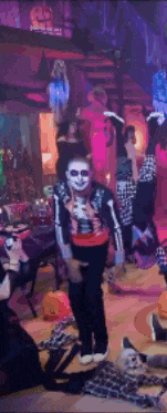 a man in a skeleton costume is standing in a room with people dressed in halloween costumes .