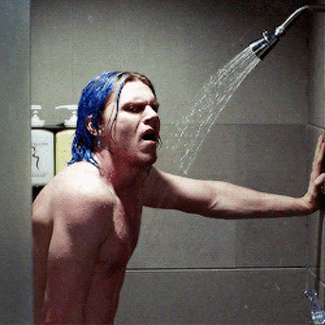 a shirtless man with blue hair is taking a shower in a bathroom
