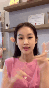 a woman in a pink top is holding a bottle and talking
