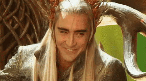 a man with long blonde hair is sitting in a chair with horns on his head .