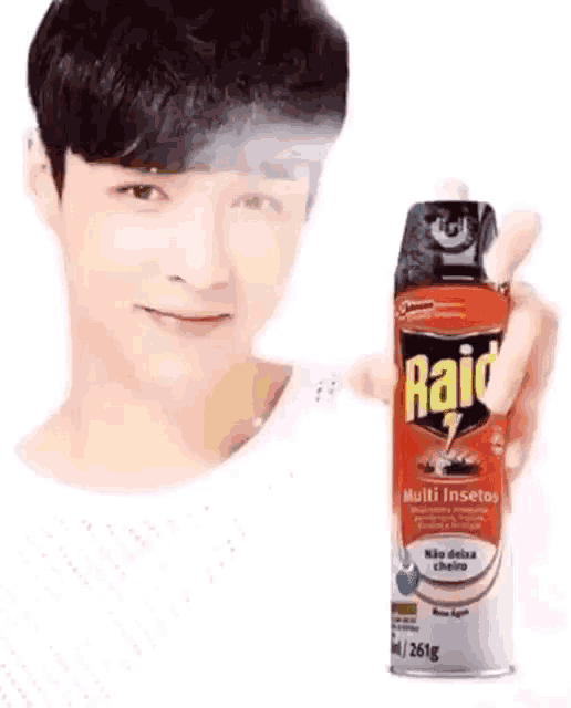 a young man is holding a bottle of raid insect spray .