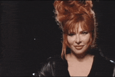 a close up of a woman 's face with her eyes closed and her hair blowing in the wind