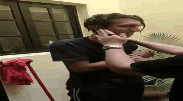 a woman is holding a man 's neck in a room with a mop .