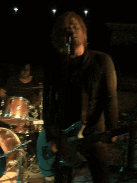a man playing a guitar in front of a drum set