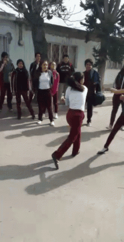 a girl in red pants is dancing in front of a crowd of people