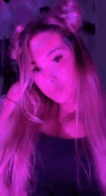 a woman with purple hair is taking a selfie in a dark room .