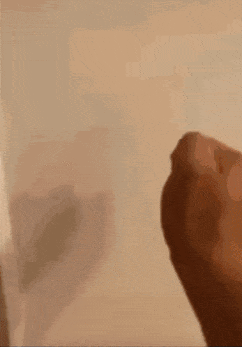 a close up of a person 's hand with a shadow on the wall