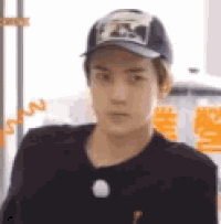 a man wearing a baseball cap and a black shirt is making a funny face .