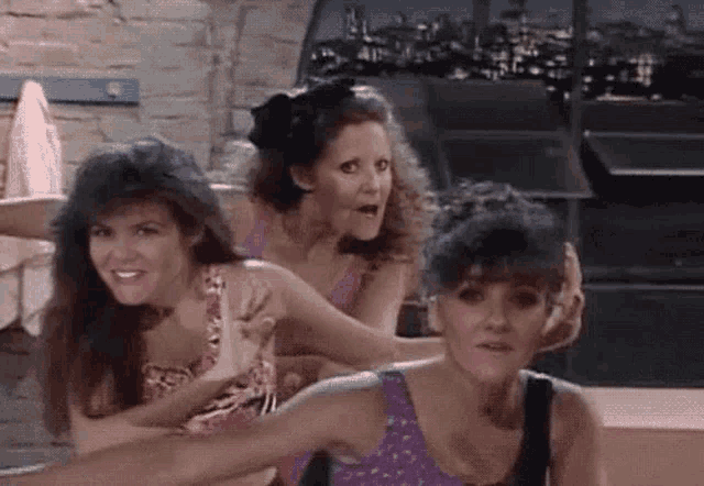 three women are standing next to each other in a room and one of them is holding another woman 's hand .